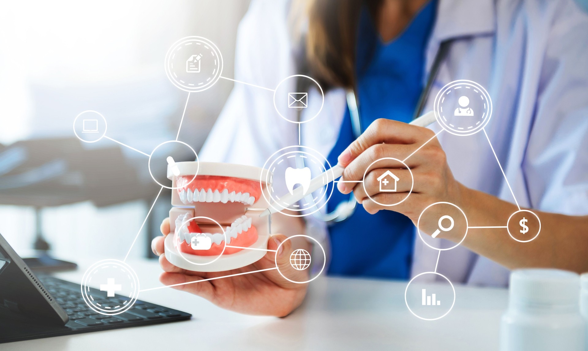 Concentrated dentist sitting at table with jaw samples tooth model and working with tablet and laptop in dental office professional dental clinic. medical doctor working with  VR icon diagram